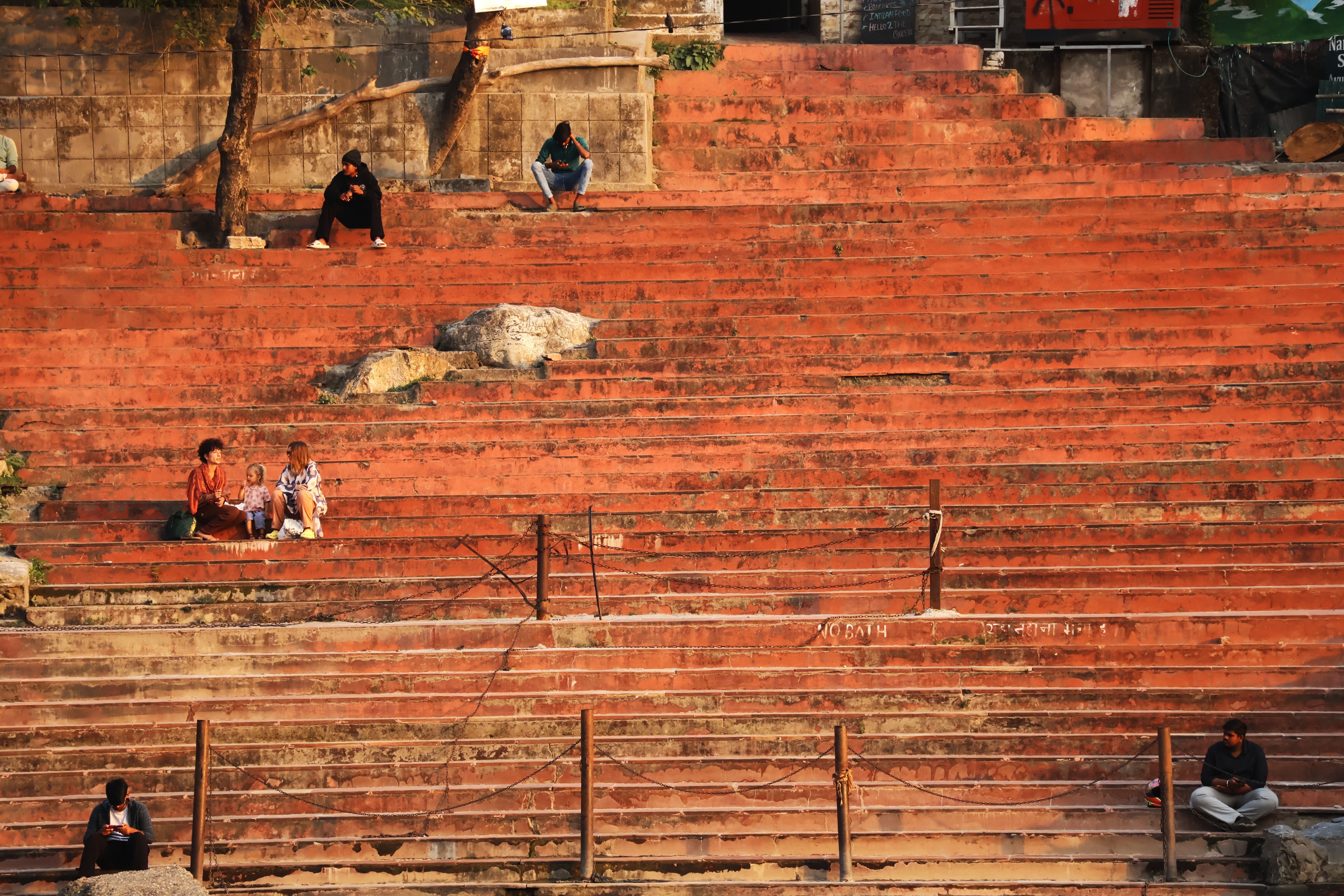 Small groups of people resting across broad terracotta steps in warm sunlight